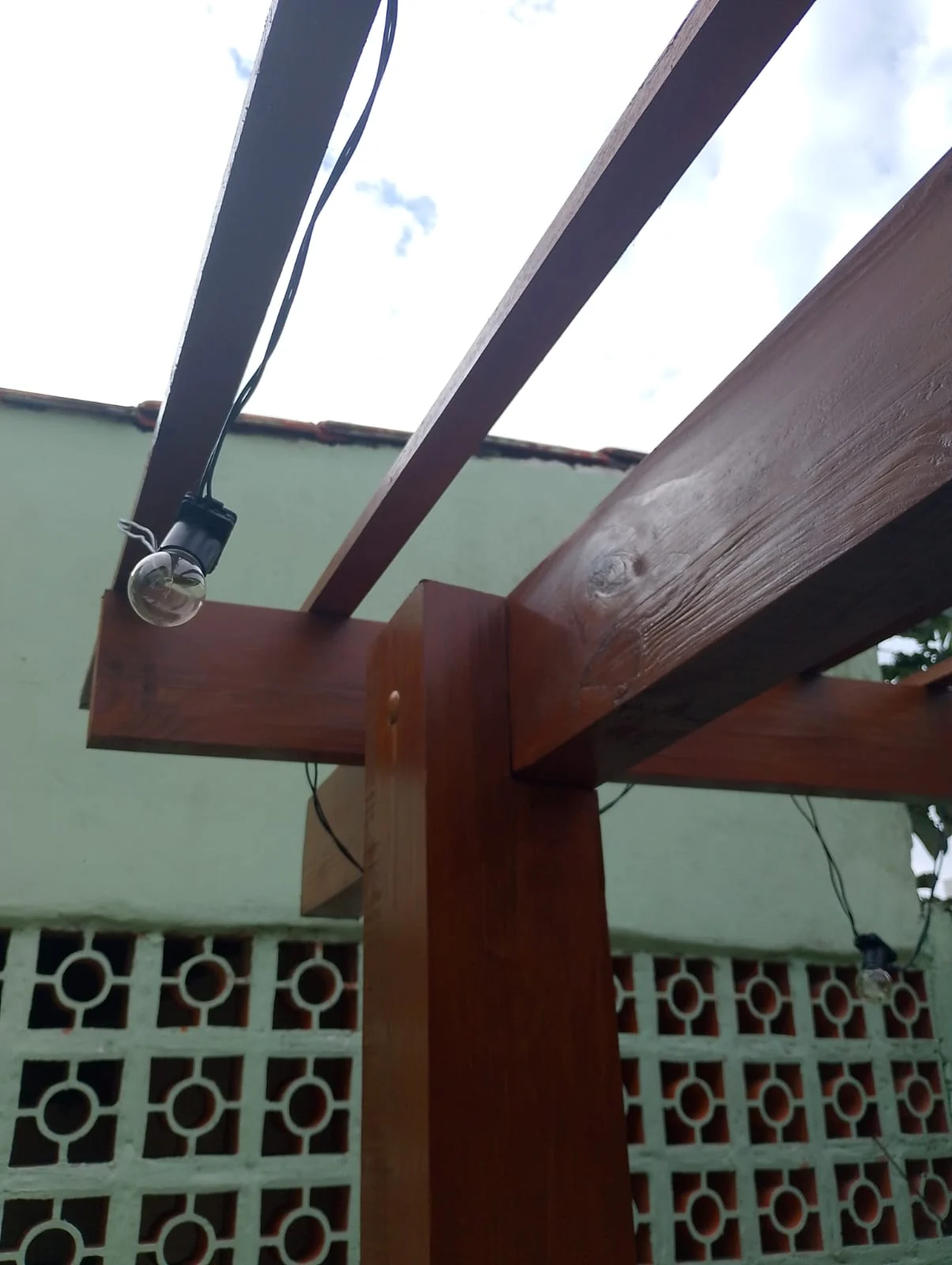 Detalhe do encaixe entre viga e pilar de madeira do pergolado